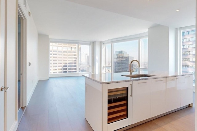 240 Devonshire St Unit 4012, Boston, MA 02110 - kitchen featuring wine cooler, light wood-style flooring, a kitchen island with sink, modern cabinets, and white cabinetry