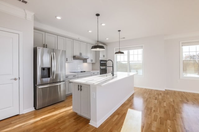 kitchen featuring a kitchen island with sink, a wealth of natural light, appliances with stainless steel finishes, and hanging light fixtures