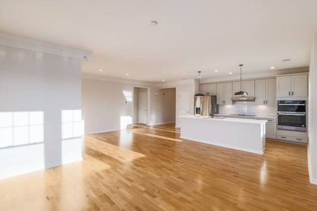 kitchen with stainless steel appliances, light hardwood / wood-style floors, gray cabinetry, a kitchen island with sink, and crown molding