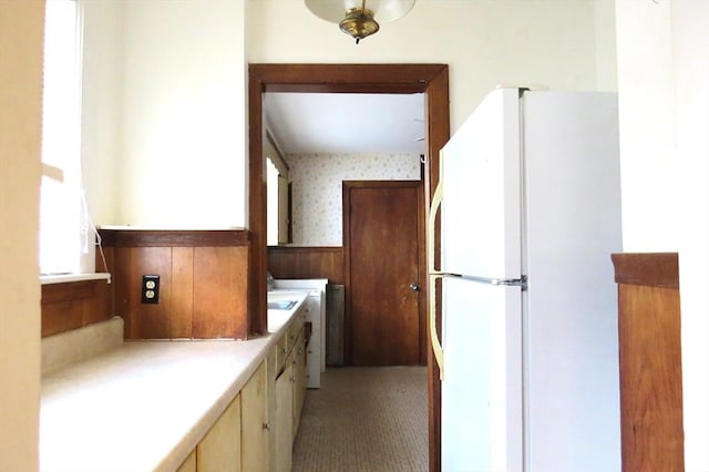 kitchen featuring light countertops, wainscoting, freestanding refrigerator, and wallpapered walls