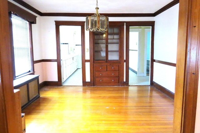 interior space with radiator heating unit, an inviting chandelier, wood finished floors, and crown molding