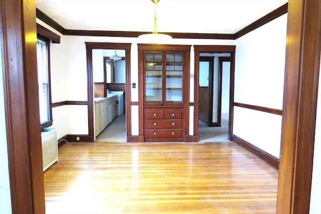 unfurnished room with radiator, crown molding, and light wood-style flooring