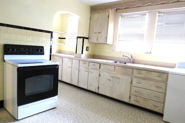 kitchen with light brown cabinets, a sink, electric stove, light countertops, and washer / clothes dryer