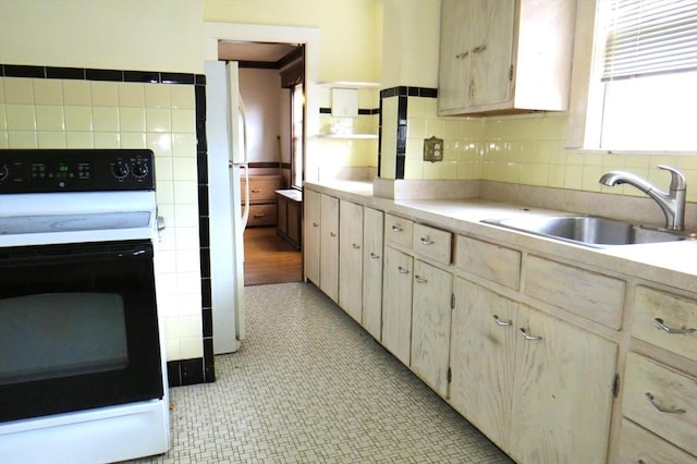 kitchen featuring electric range oven, light countertops, a sink, and tile walls