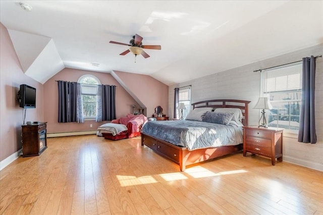 bedroom featuring lofted ceiling, a baseboard heating unit, and light wood-type flooring