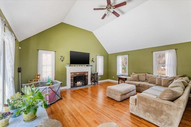 living room featuring vaulted ceiling, hardwood / wood-style floors, ceiling fan, and a fireplace