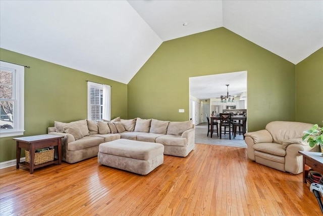 living room featuring an inviting chandelier, high vaulted ceiling, and light wood-type flooring