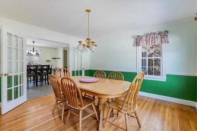 dining area with an inviting chandelier, ornamental molding, and light hardwood / wood-style flooring