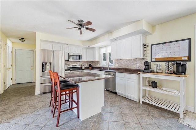 kitchen featuring white cabinetry, tasteful backsplash, a center island, a kitchen breakfast bar, and stainless steel appliances