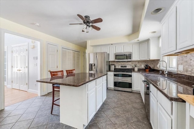 kitchen featuring sink, appliances with stainless steel finishes, a kitchen breakfast bar, a kitchen island, and white cabinets