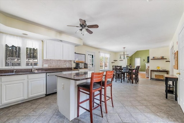 kitchen featuring stainless steel dishwasher, a kitchen bar, a center island, and white cabinets