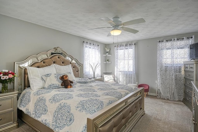 bedroom featuring light carpet, a textured ceiling, a ceiling fan, and baseboards