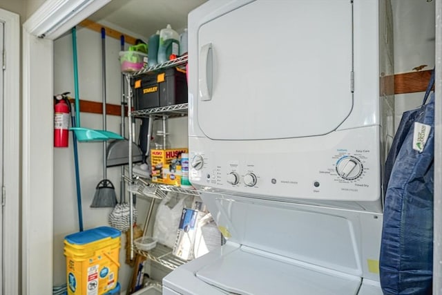 clothes washing area featuring stacked washer / dryer and laundry area