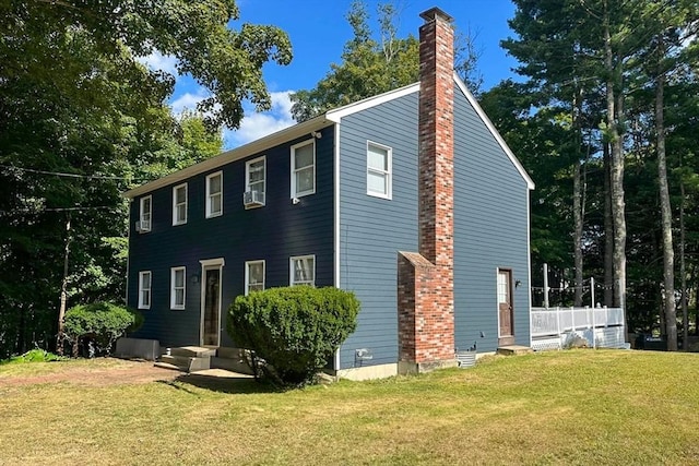 view of side of property featuring a chimney and a lawn