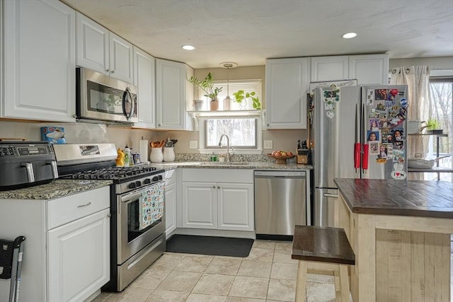 kitchen featuring light tile patterned floors, recessed lighting, stainless steel appliances, a sink, and white cabinetry