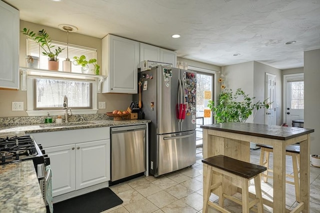 kitchen with light stone counters, appliances with stainless steel finishes, decorative light fixtures, and white cabinets