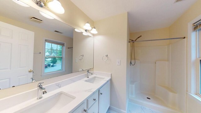 full bath with a shower, double vanity, and baseboards