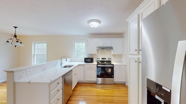 kitchen featuring appliances with stainless steel finishes, under cabinet range hood, a sink, and light wood-type flooring