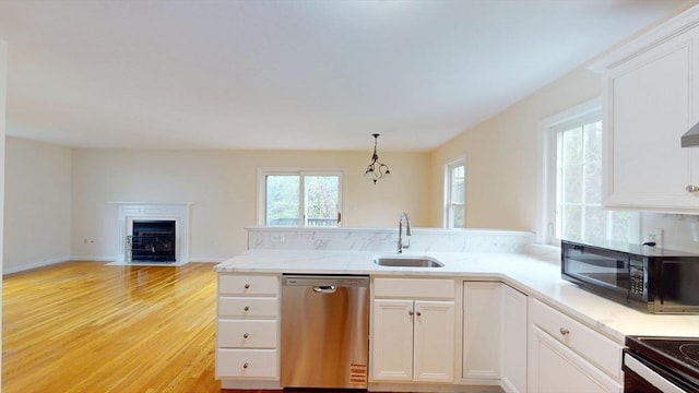 kitchen with stainless steel dishwasher, a sink, a peninsula, black microwave, and white cabinetry