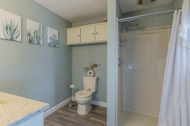 bathroom featuring toilet, wood finished floors, a shower stall, baseboards, and vanity