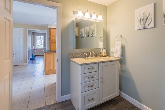 bathroom featuring tile patterned flooring, baseboard heating, vanity, and baseboards