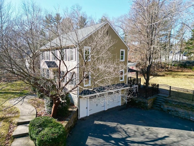 view of front facade with a gate, aphalt driveway, an attached garage, and fence