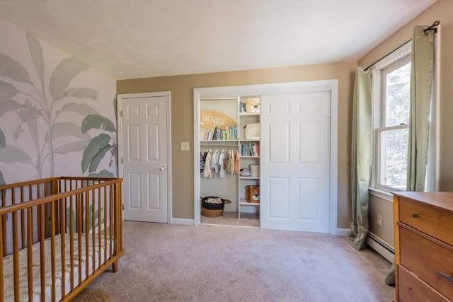 bedroom featuring light carpet, a closet, baseboards, and a baseboard radiator