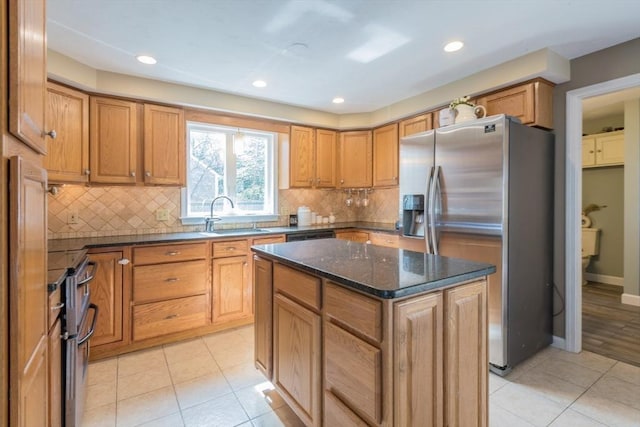 kitchen with light tile patterned floors, decorative backsplash, stainless steel fridge, and a sink