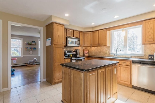 kitchen featuring a sink, dark stone countertops, backsplash, a kitchen island, and appliances with stainless steel finishes