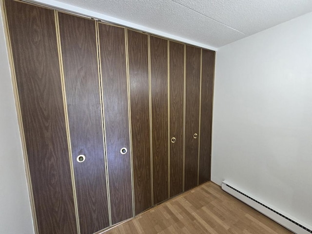 17 Skyline Dr Unit 3, Braintree, MA 02184 - unfurnished bedroom featuring baseboard heating, wood finished floors, a closet, and a textured ceiling