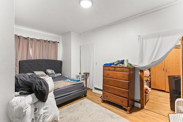 bedroom with a baseboard radiator and light wood-style floors