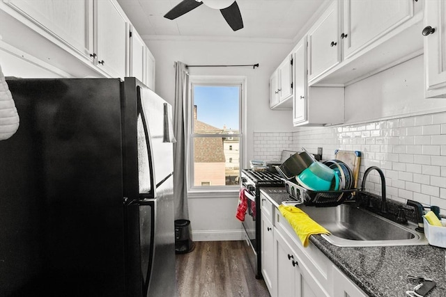 kitchen featuring decorative backsplash, dark wood-style flooring, freestanding refrigerator, white cabinetry, and a sink