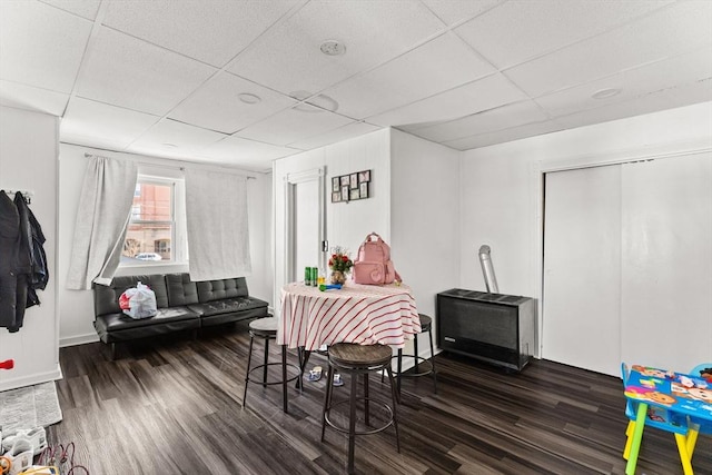 recreation room with a drop ceiling, wood finished floors, and baseboards