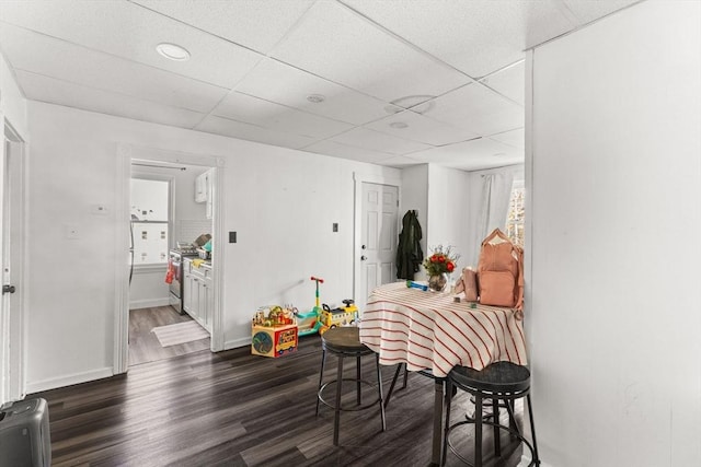 dining space with a paneled ceiling, dark wood-style floors, and baseboards