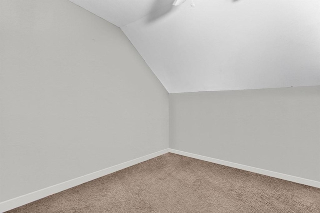 additional living space featuring carpet, vaulted ceiling, and baseboards