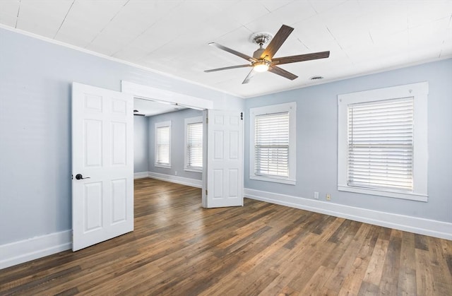 empty room with dark wood-type flooring, ornamental molding, baseboards, and a ceiling fan