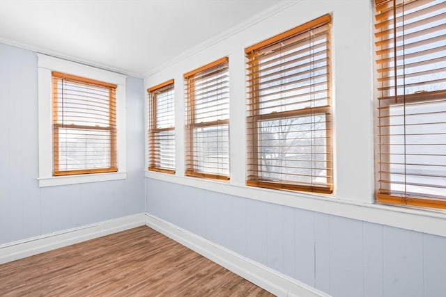 unfurnished room with ornamental molding, baseboards, and wood finished floors