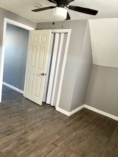 additional living space featuring a ceiling fan, lofted ceiling, dark wood-style flooring, and baseboards