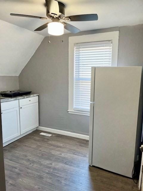 kitchen with lofted ceiling, white cabinetry, baseboards, freestanding refrigerator, and dark wood finished floors