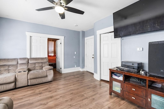 living room featuring light wood finished floors, a ceiling fan, and baseboards