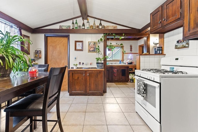 kitchen featuring tasteful backsplash, light tile patterned floors, lofted ceiling with beams, light countertops, and white range with gas stovetop