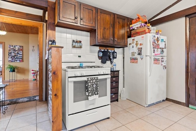 kitchen with light tile patterned floors, white appliances, and vaulted ceiling