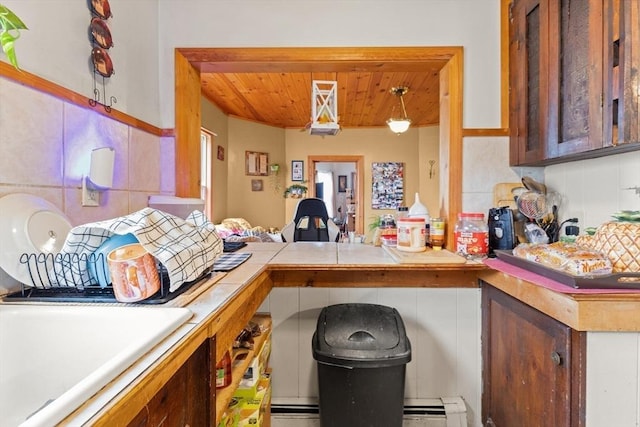 kitchen with wooden ceiling, tile counters, a peninsula, a baseboard radiator, and a sink