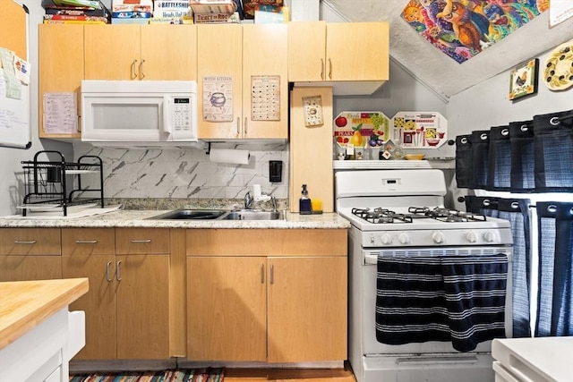 kitchen featuring tasteful backsplash, white appliances, a sink, and lofted ceiling