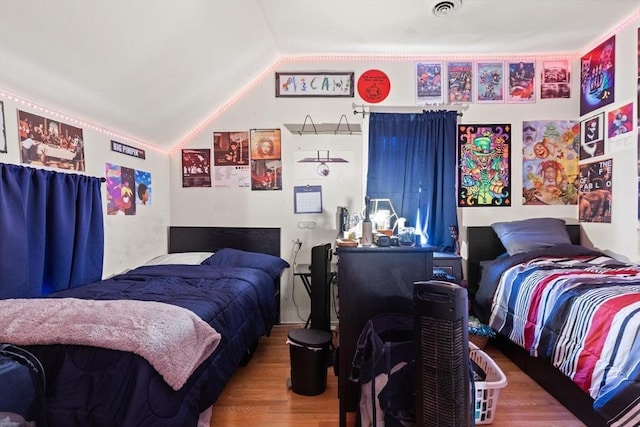 bedroom with visible vents, wood finished floors, and lofted ceiling