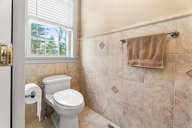 bathroom featuring tile walls, tile patterned floors, and toilet