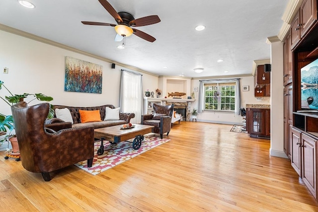 living area featuring ornamental molding, ceiling fan, and light wood-style flooring