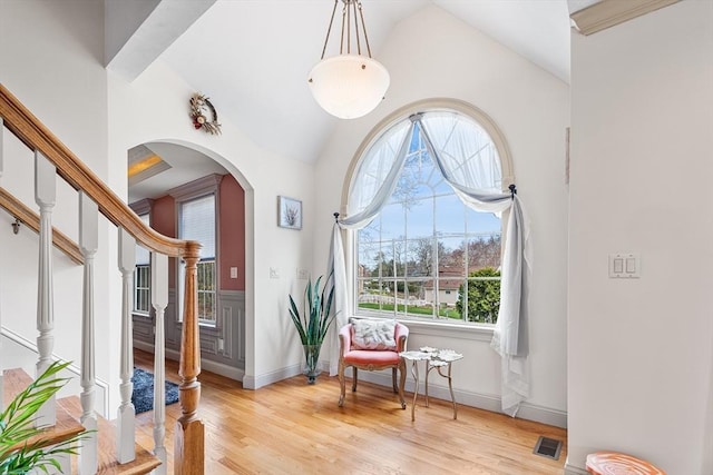 sitting room featuring visible vents, arched walkways, stairway, and light wood-style flooring