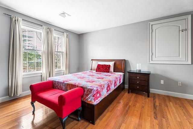 bedroom featuring baseboards, visible vents, and wood finished floors