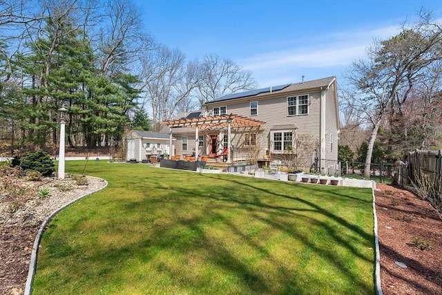 rear view of property featuring a pergola, a patio, an outbuilding, roof mounted solar panels, and fence